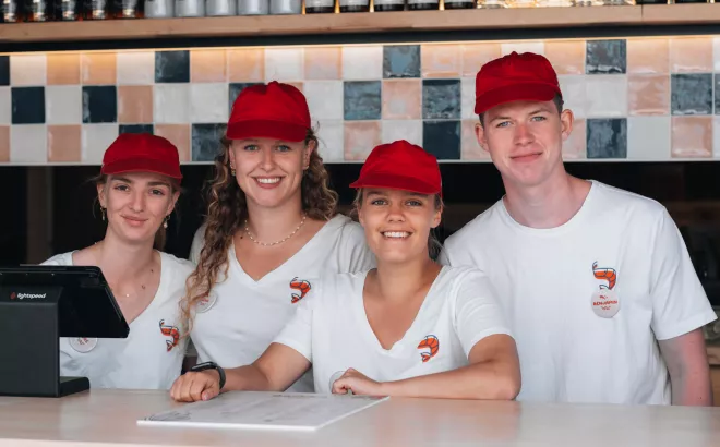Vier studenten in uniform die werken achter de kassa