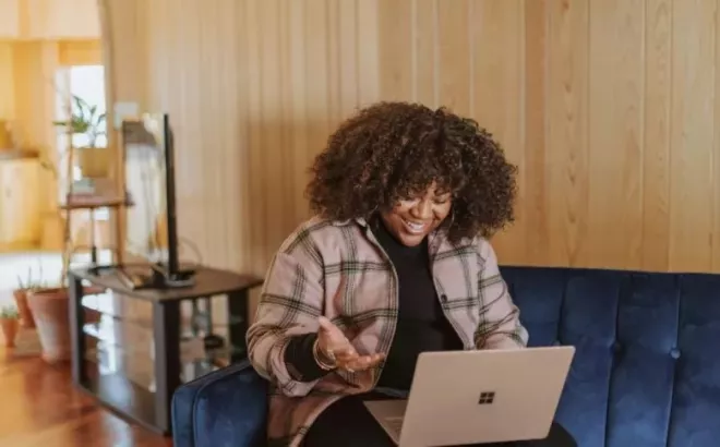Une jeune femme rédige une lettre de motivation sur son ordinateur portable.
